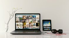 Laptop z wynajmu laptopa leży na stole wraz z tabletem, słuchawkami i wazonem